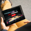 A person sitting on the ground holding a tablet in one hand and watching a livestream of a sports broadcast. The screen says &quot;Live Streaming&quot; and shows a basketball court.