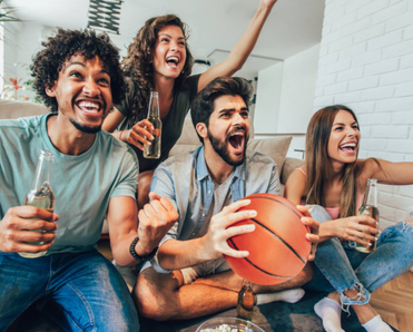 Group of friends with drinks watching a basketball game. 